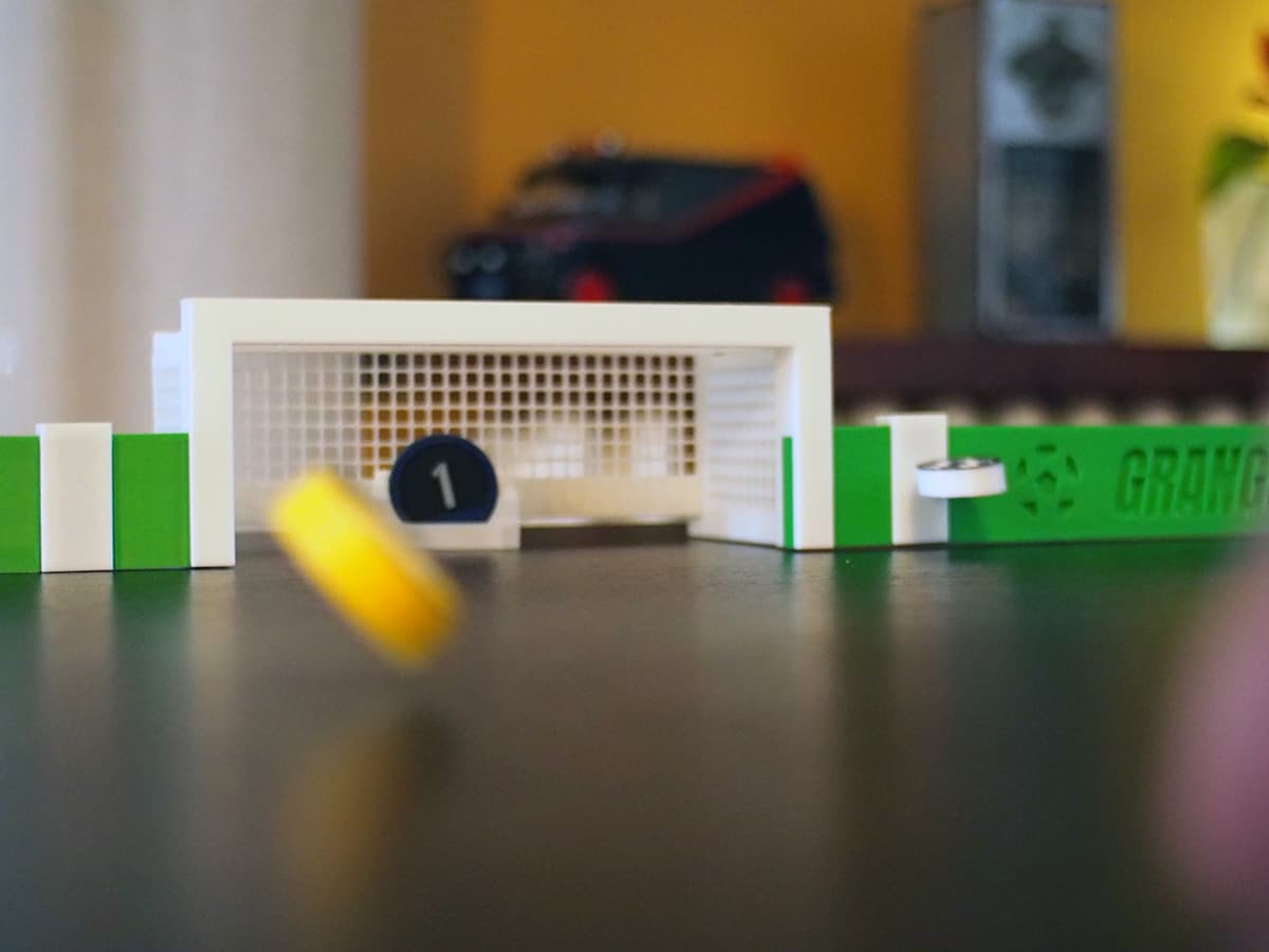 A GGx player taking a shot towards the goal during a tabletop football match.